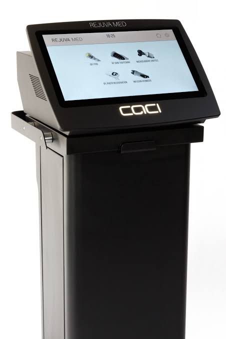 6 - Dr Hans Clinics - Dr Hans Clinics Tall black medical kiosk with a tilted touchscreen displaying treatment icons and the COCCI logo.