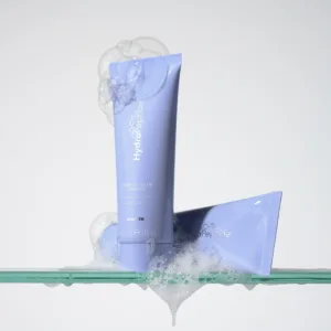 Foaming-Cream-Cleanser-Hero-Image-01-3000px - Dr Hans Clinics Blue HydroPeptide foaming cleanser tube surrounded by bubbles on a pale background, close-up.