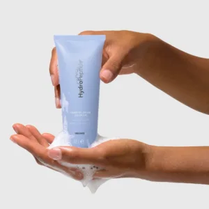 Foaming-Cream-Cleanser-Hero-Image-02-3000px - Dr Hans Clinics Hands hold a light blue tube of foaming cream cleanser, with white foam dripping onto the palms below.