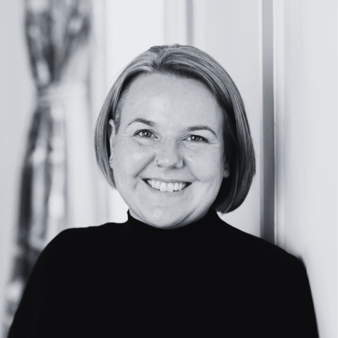 Head-and-shoulders portrait of a smiling woman with short hair wearing a black turtleneck.
