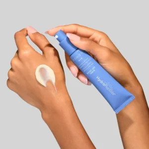 Nimni-Day-Cream-Hero-Image-03-3000px - Dr Hans Clinics Hands apply white cream from a blue tube onto a forearm; close-up skincare action