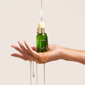 RadianceSerumHandShot2 - Dr Hans Clinics Exuviance Radiance Serum bottle held on a hand with golden serum dripping down the wrist and palm