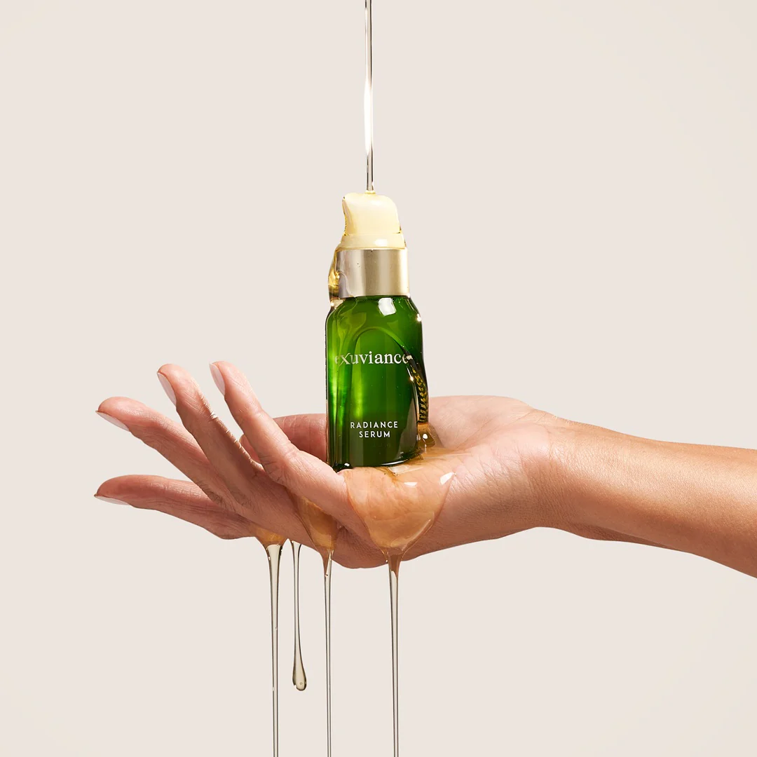 RadianceSerumHandShot2 - Dr Hans Clinics Exuviance Radiance Serum bottle held on a hand with golden serum dripping down the wrist and palm